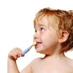 A happy young boy brushes his teeth